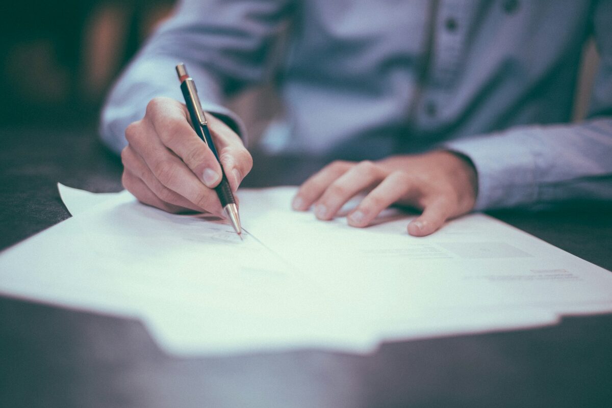 A document being signed with a pen — the everyday work of a notary public